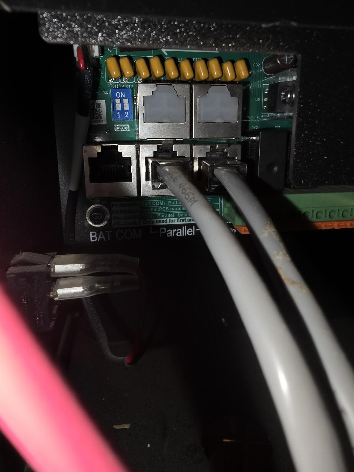 Inverter communications ports with the blue DIP switch and two grey cables in the Parallel ports