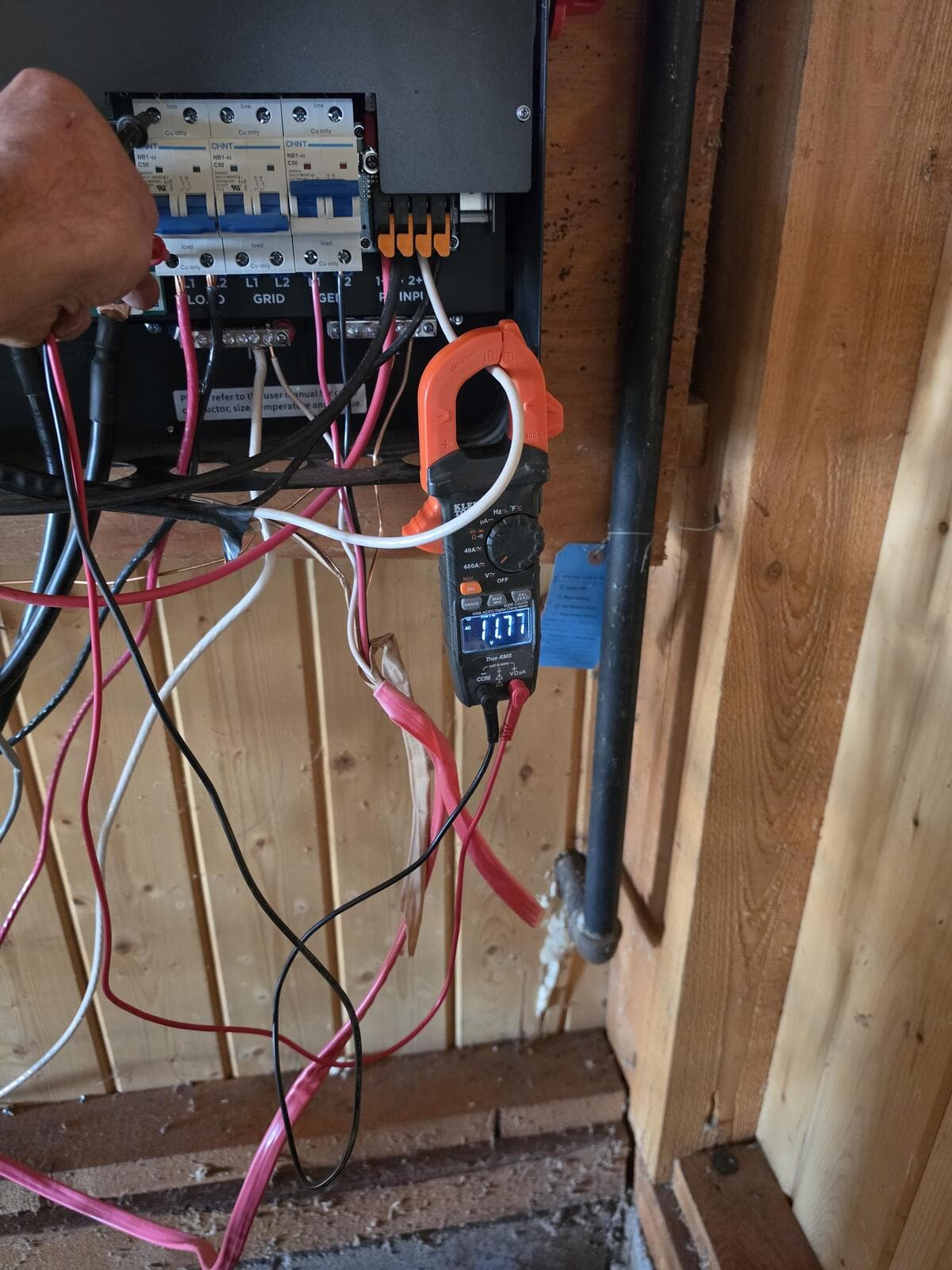 Clamp meter reading 11.77 volts across one pole of the inverter LOAD breaker